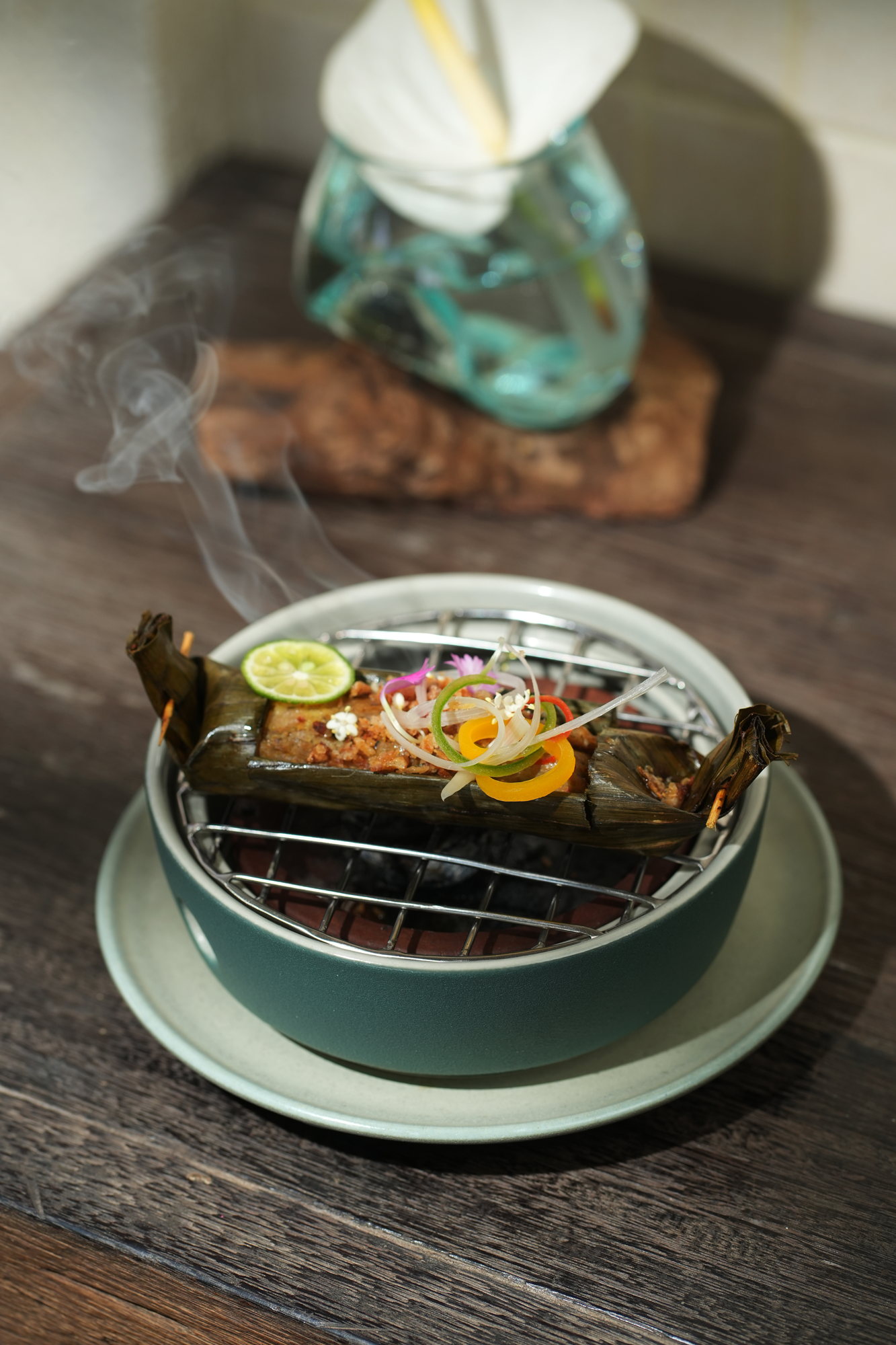 A banana-leaf parcel grilled over charcoal at the table at ARUM, Paradisus by Melia Bali