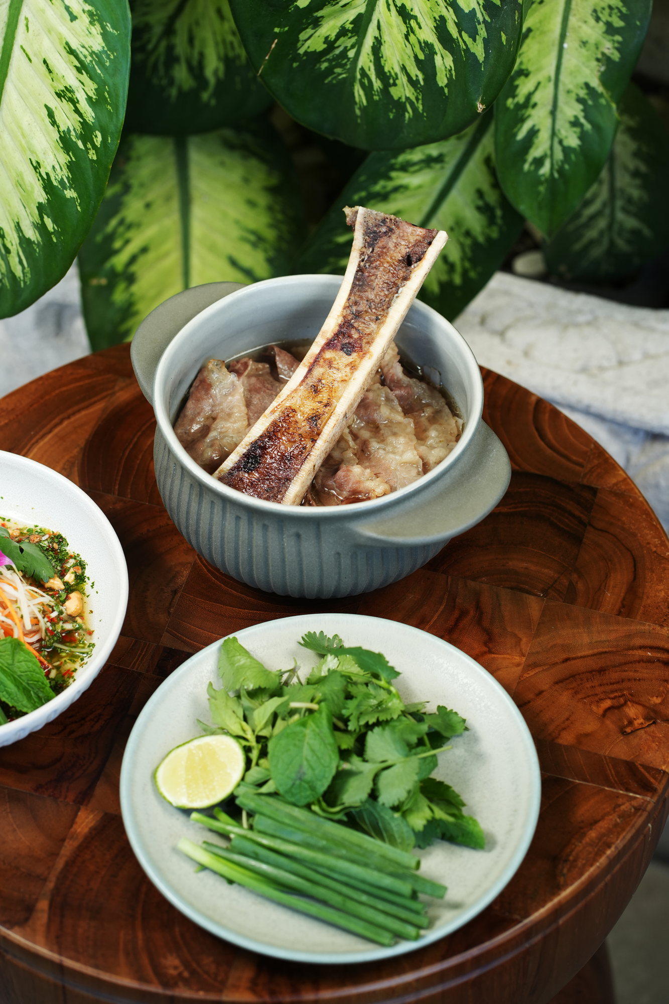 Beef and bone marrow soup with a plate of fresh herbs and lime at ARUM, Paradisus by Melia Bali