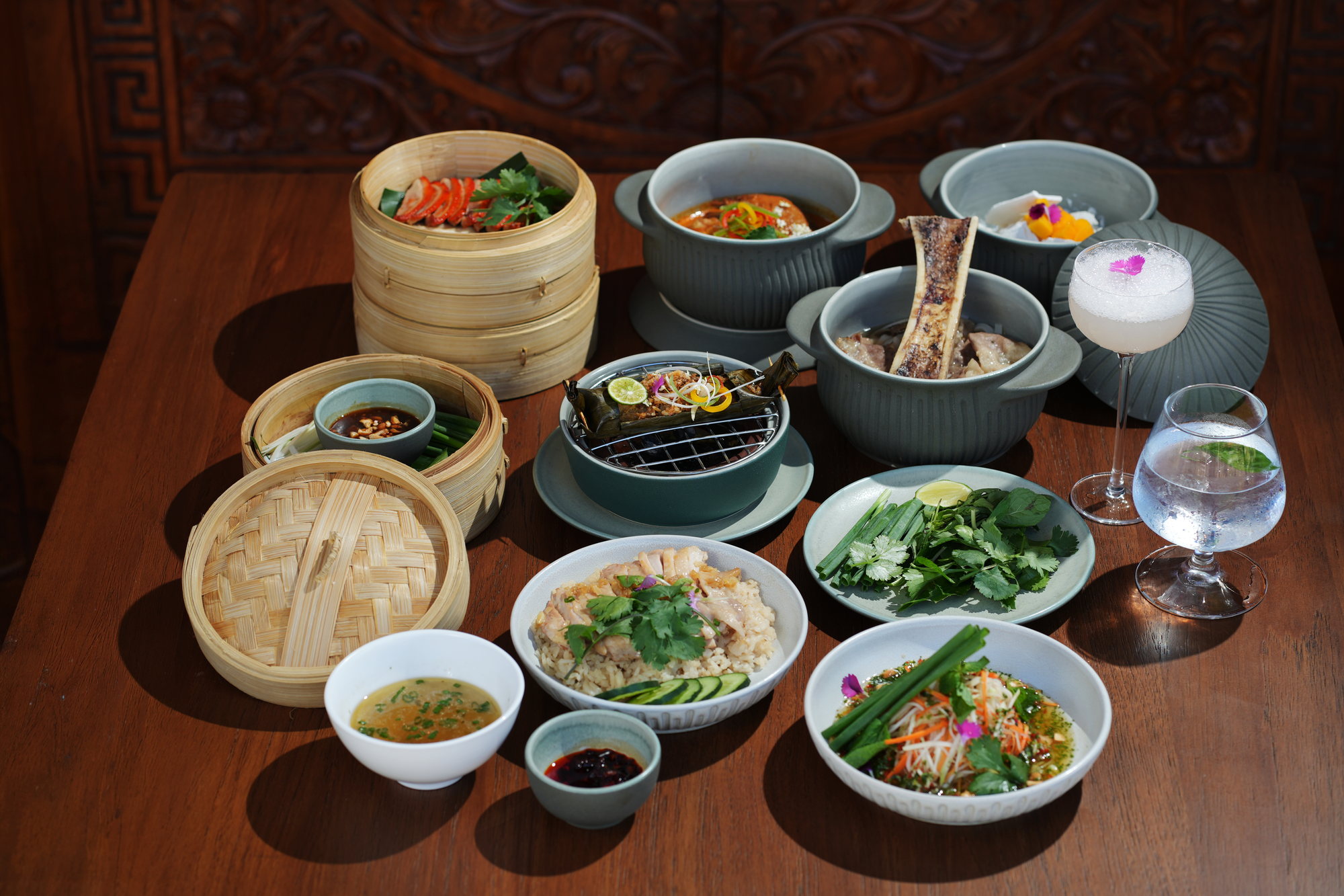 A full table of dishes at ARUM, Paradisus by Melia Bali: bamboo steamers, clay pots, rice, herbs and cocktails