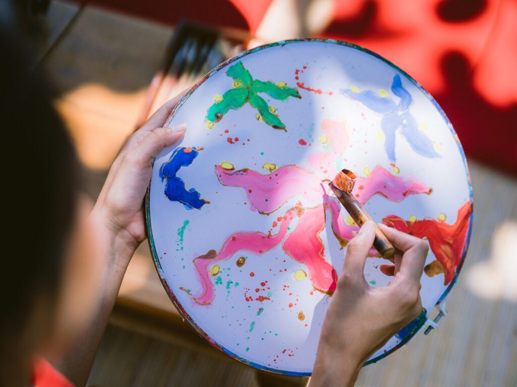 A guest painting a batik design with a canting on a round frame during the Batik and Art class at Paradisus by Meliá Bali