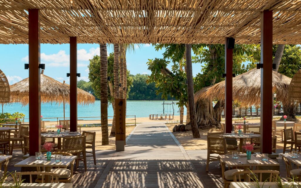 Kanna Beach Restaurant at Paradisus by Meliá Bali, tables under a driftwood canopy looking onto the lagoon and beach