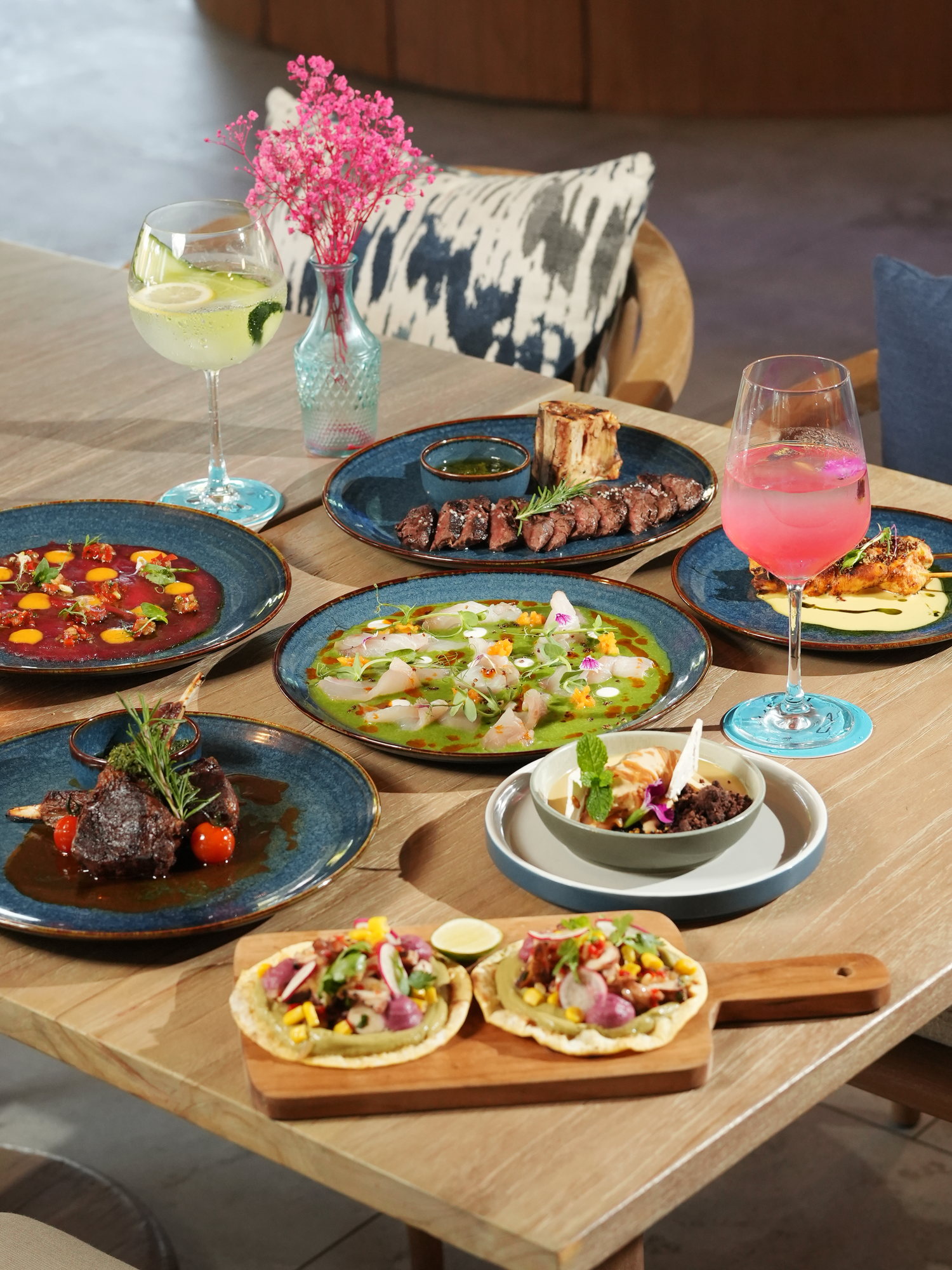A table of dishes at Kanna Beach, Paradisus by Melia Bali: grilled steak with bone marrow, lamb chops, beef carpaccio, ceviche, skewers, octopus tostadas and cocktails