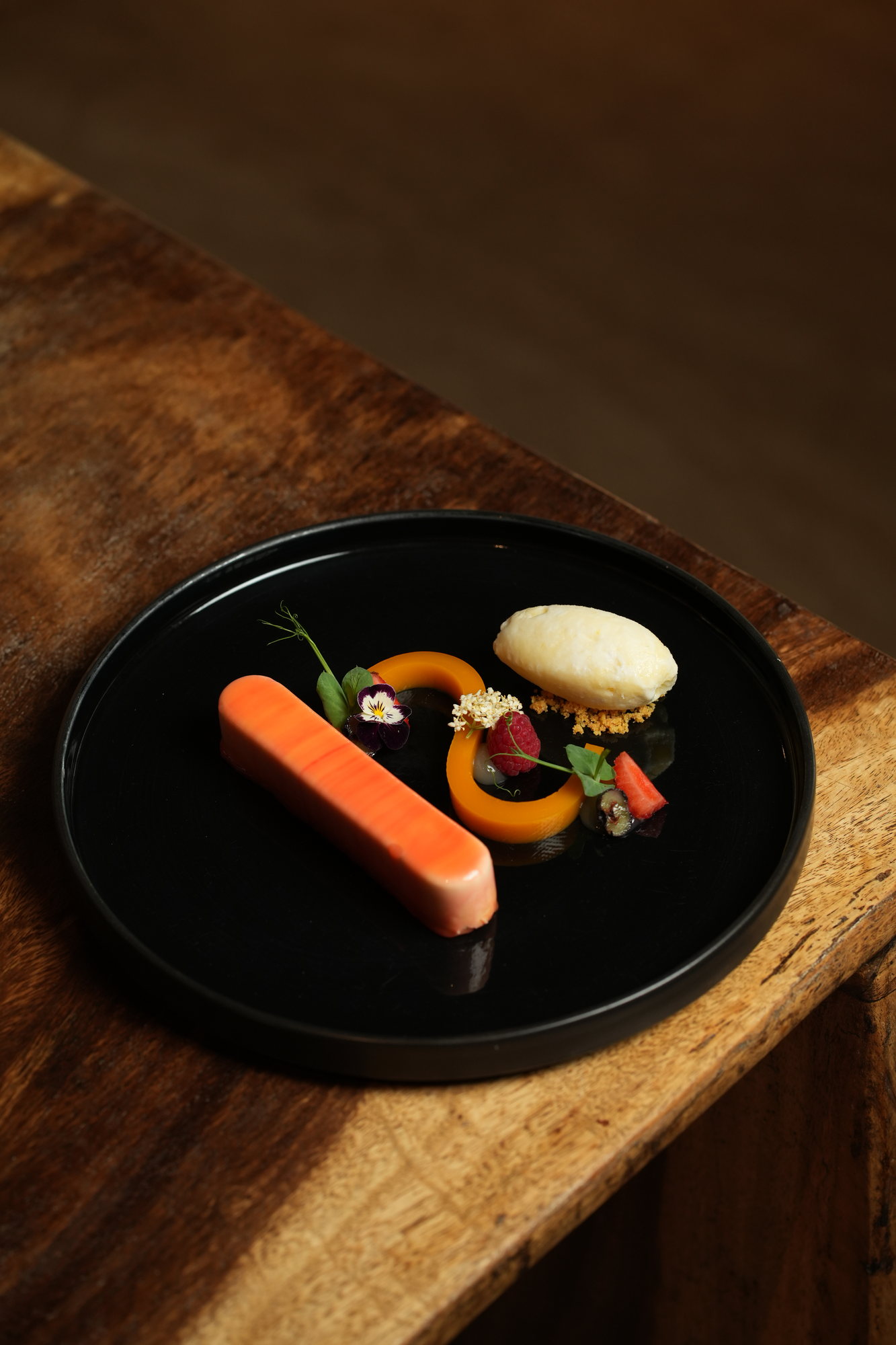 A layered fruit terrine with sorbet, raspberry and elderflower on a black plate at Malva, Paradisus by Melia Bali