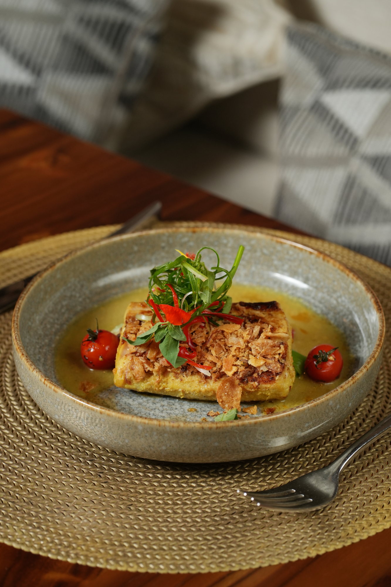 Seared fish in a yellow curry broth topped with crisp shallots, chilli and herbs, with blistered tomatoes at Malva, Paradisus by Melia Bali