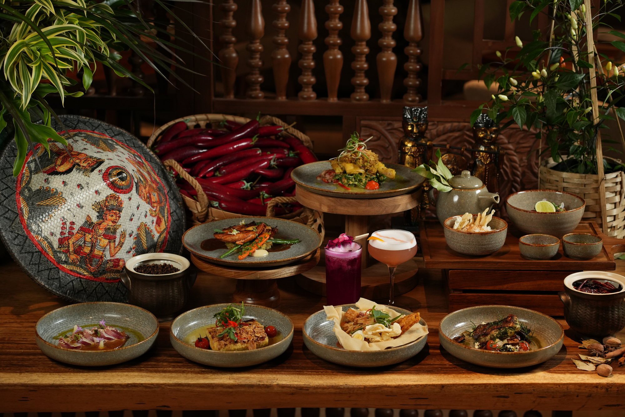 A table of Indonesian dishes at Malva, Paradisus by Melia Bali, set out with baskets of red chillies and carved Balinese figures