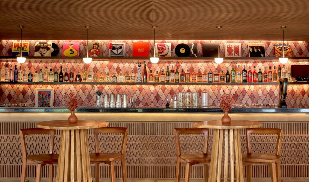 Mixton Bar at Paradisus by Meliá Bali, a back bar of spirits under a shelf of vinyl records and pink diamond tiles