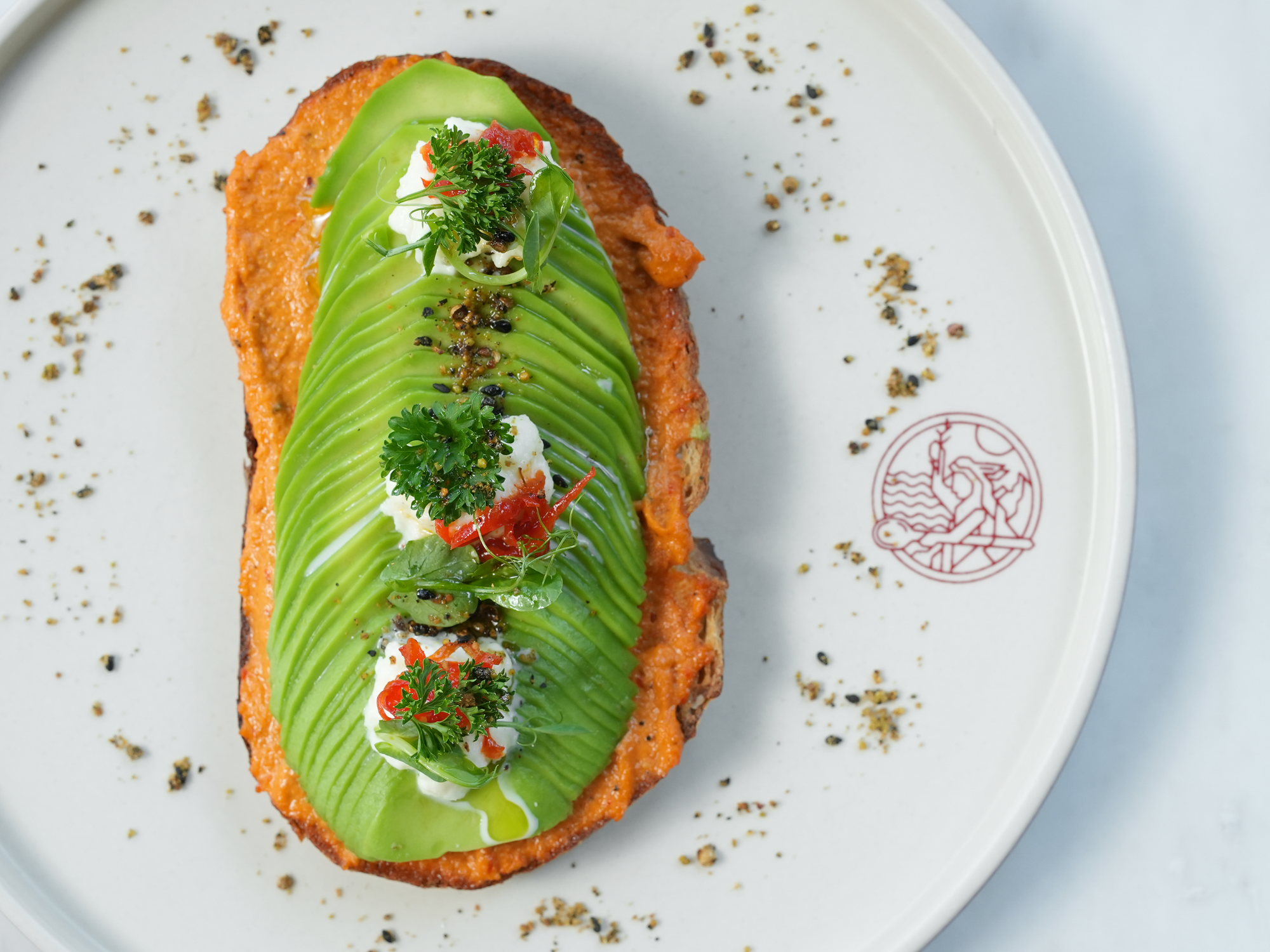Sliced avocado fanned over toast with romesco, curd cheese, herbs and dukkah at Peseta, Paradisus by Melia Bali