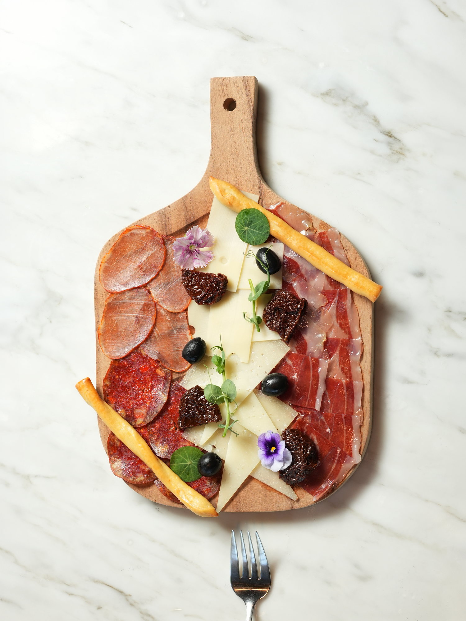 A board of Spanish cured meats and cheeses with olives, sun-dried tomatoes and breadsticks at Peseta, Paradisus by Melia Bali