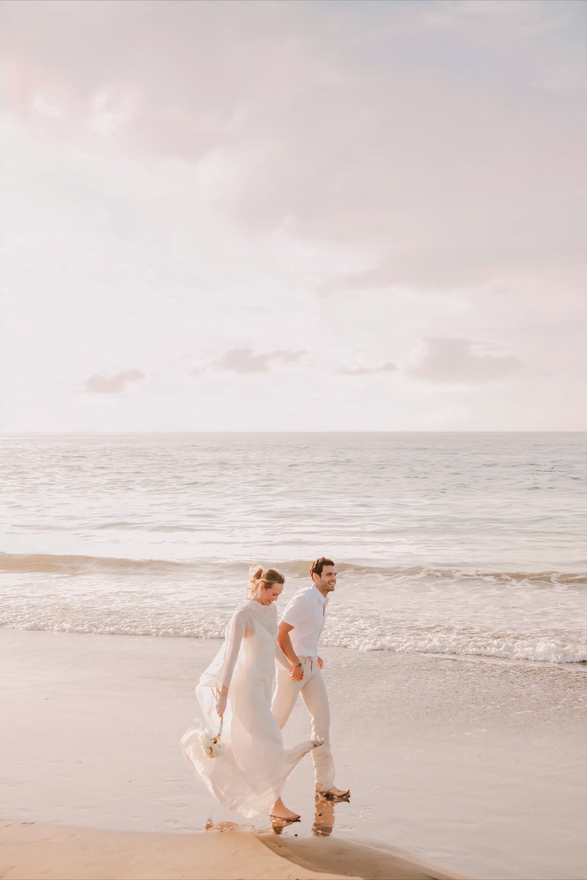 A bride and groom walking hand in hand along the shoreline at Paradisus by Meliá Bali in Nusa Dua