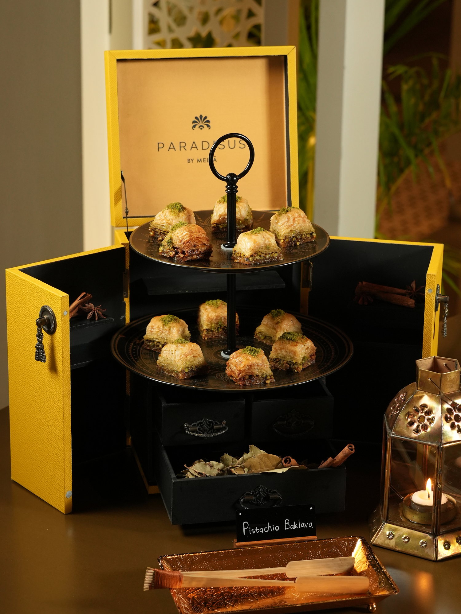 Pistachio baklava on tiered brass trays inside a yellow Paradisus chest, with cinnamon and star anise in the drawers, at Samira