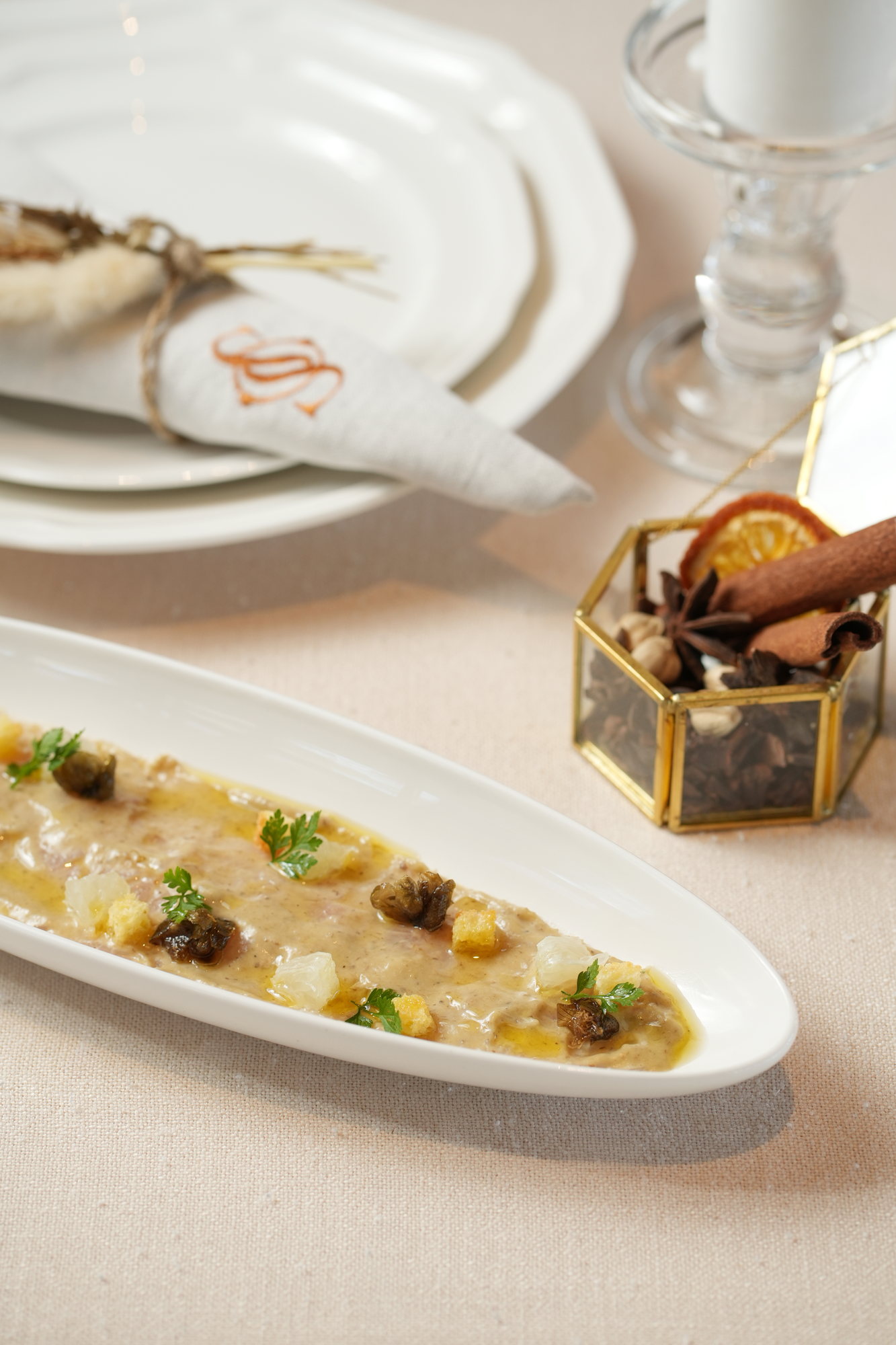 A thin carpaccio spread the length of an oval plate, dressed with citrus segments, fried capers, croutons and chervil at Sante, Paradisus by Melia Bali