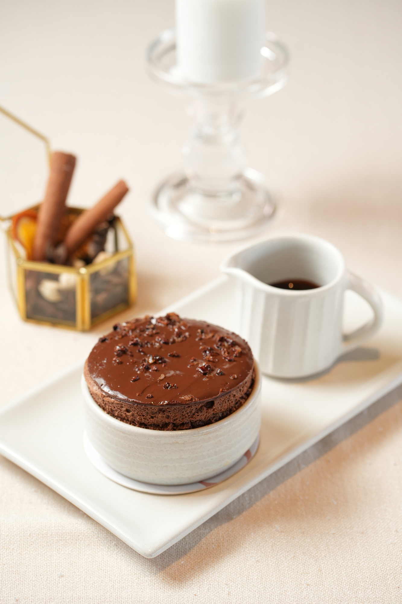 A chocolate souffle topped with ganache and cacao nibs, with a jug of warm sauce, at Sante, Paradisus by Melia Bali