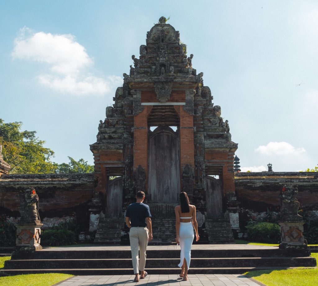 Two guests walking up to the carved candi bentar gate of Taman Ayun, the royal temple of Mengwi, on a Destination Inclusive excursion from Paradisus by Meliá Bali