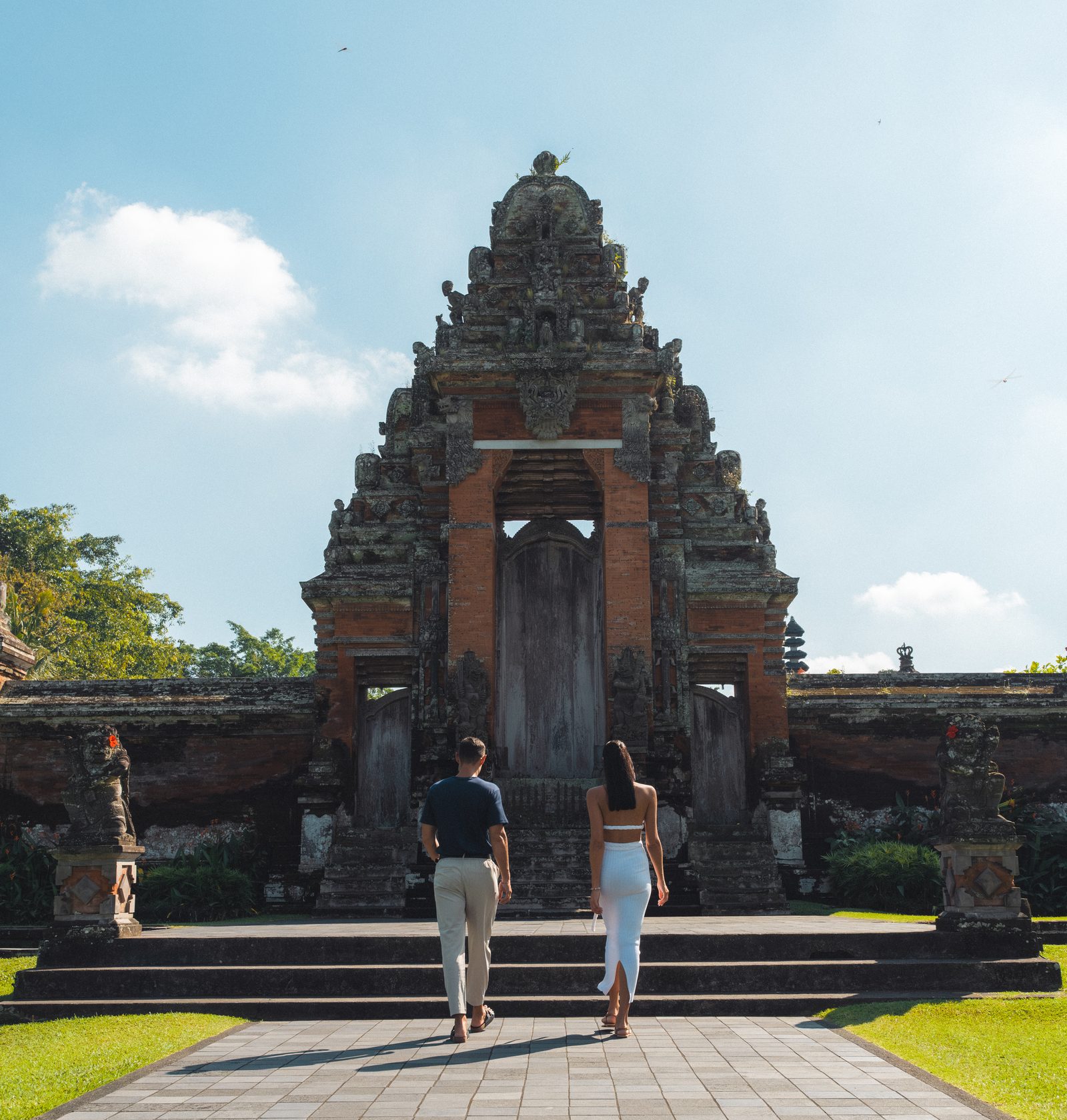 Two guests walking up to the carved candi bentar gate of Taman Ayun, the royal temple of Mengwi, on a Destination Inclusive excursion from Paradisus by Meliá Bali
