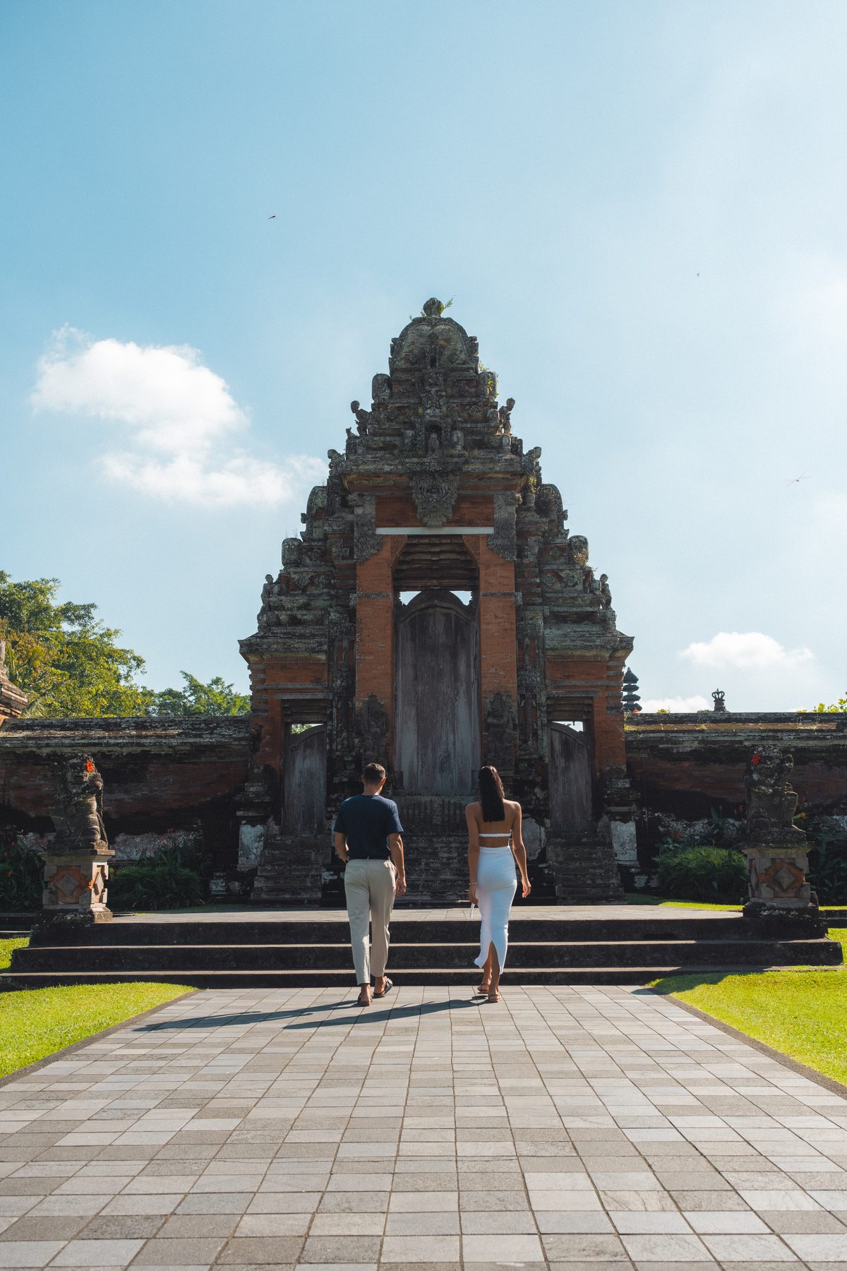 Two guests walking up to the carved candi bentar gate of Taman Ayun, the royal temple of Mengwi, on a Destination Inclusive excursion from Paradisus by Meliá Bali