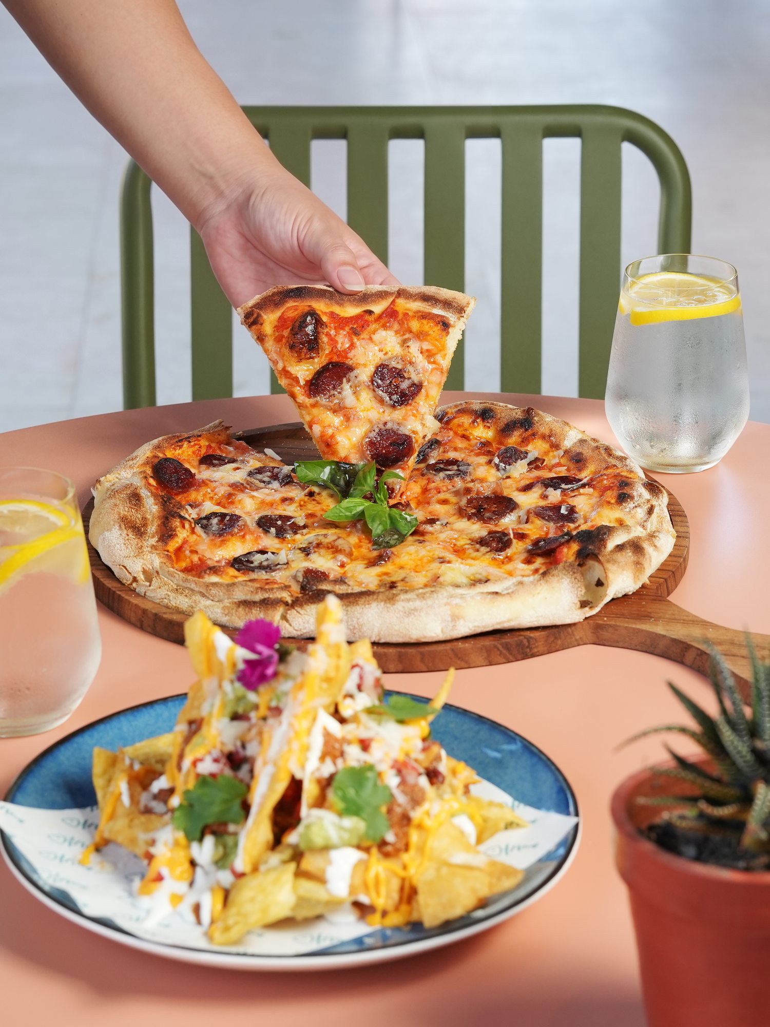 A slice lifted from a chorizo and basil pizza on a wooden board at The Shack, Paradisus by Melia Bali