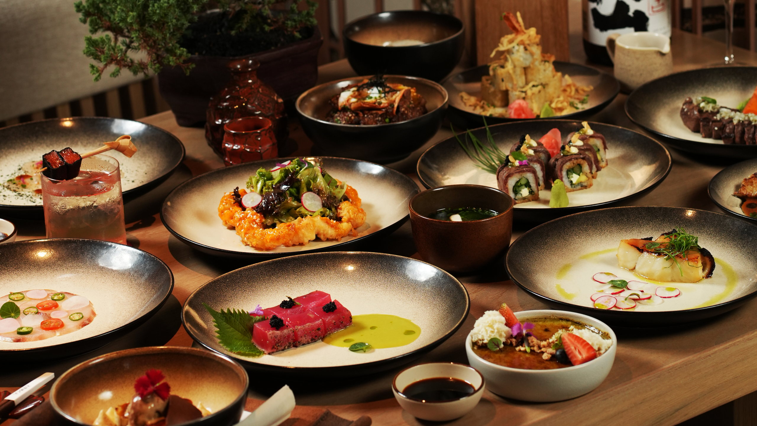 A table of Japanese dishes at Tokimeku, Paradisus by Meliá Bali: tuna tataki, sushi rolls, tempura, miso soup and black cod, with sake and cocktails