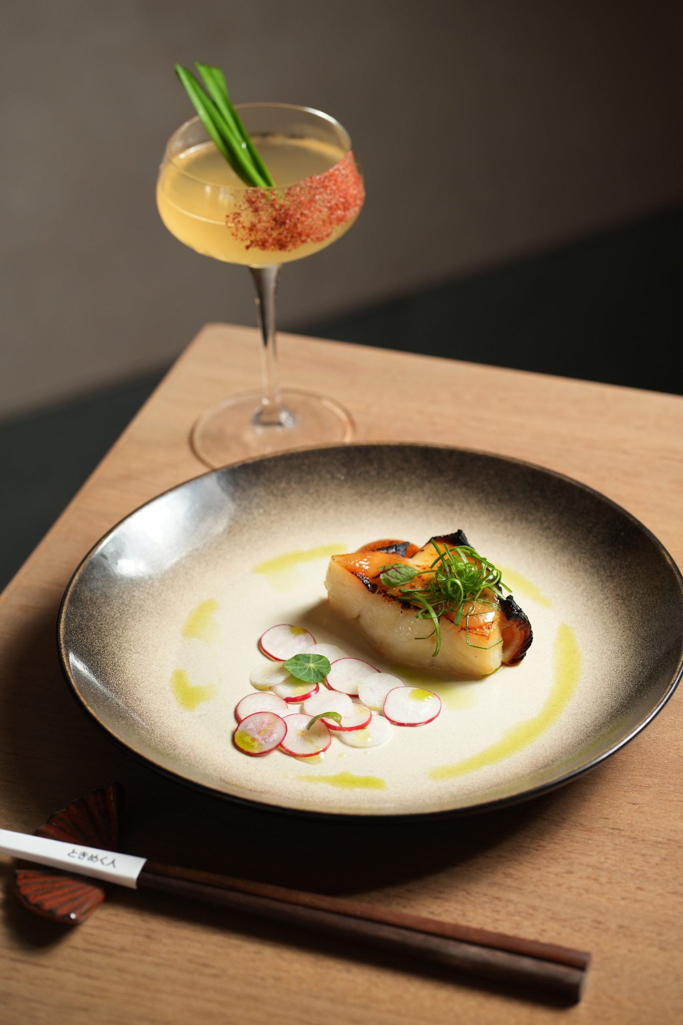 Miso-glazed black cod with sliced radish, spring onion and herb oil, with a cocktail alongside, at Tokimeku, Paradisus by Melia Bali