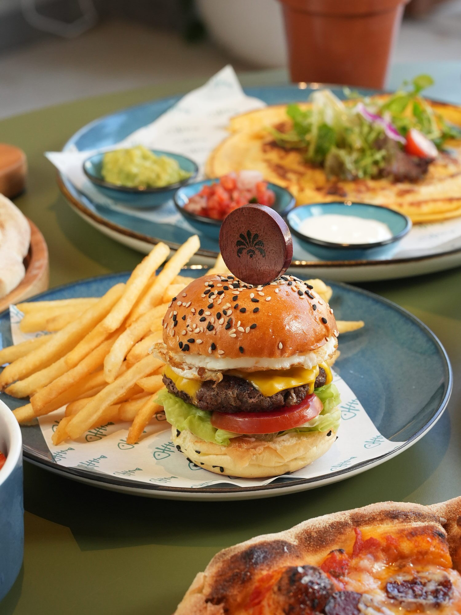 A cheeseburger with a fried egg, tomato and lettuce on a sesame brioche bun, served with fries at The Shack, Paradisus by Melia Bali